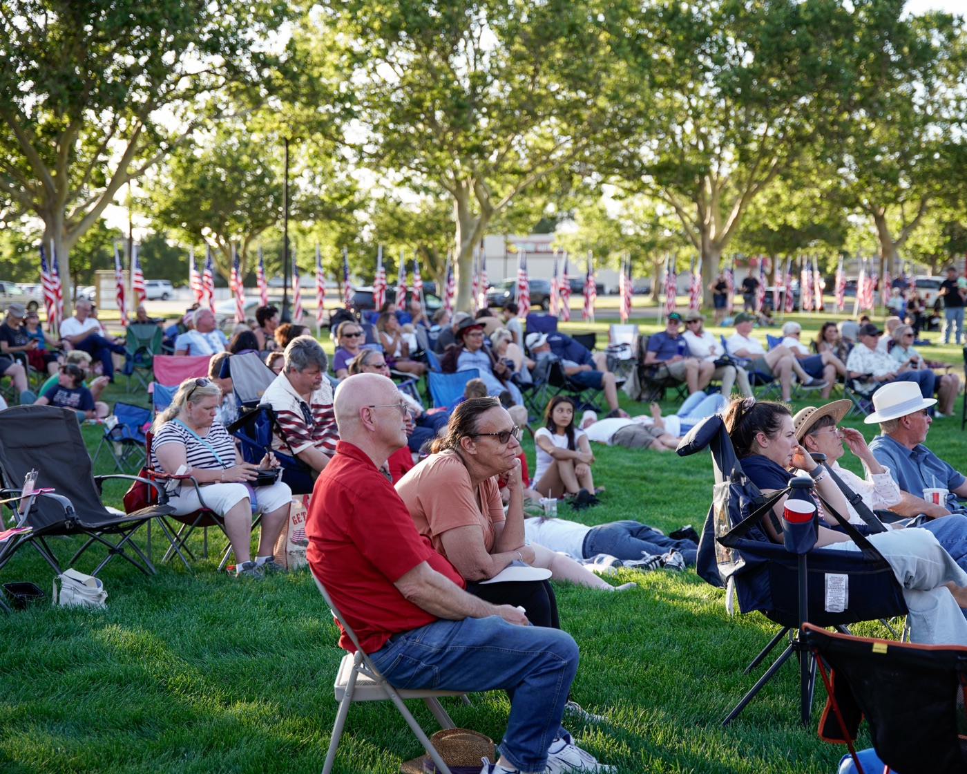 Families gathered for an evening event with rows of American flags